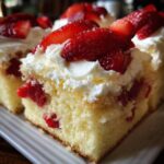 Close-up of a square slice of strawberry shortcake trifle showing layers of sponge cake, macerated strawberries, and whipped cream topping.