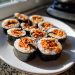 A plate of freshly sliced tuna kimbap rolls showing the bright orange tuna filling surrounded by white rice and dark seaweed.