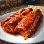 Three rolled cheese enchiladas smothered in vibrant red sauce, served on a white plate.