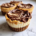 A close-up of one of the decadent cookie butter cheesecake cups with a swirled chocolate topping.