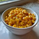 Close-up of creamy honey butter corn kernels coated in a rich sauce, served in a white bowl.