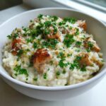 Close-up of creamy one pot chicken and rice topped with seared chicken pieces, grated parmesan, and fresh parsley.