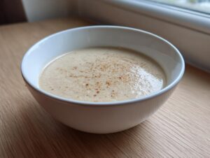 A close-up of creamy roasted cauliflower soup topped with spices in a white bowl.