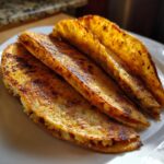 Close-up of three golden-brown, crispy fried potato tacos lined up on a white plate.