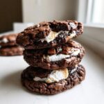 Stack of three gooey hot chocolate cookies filled with melted marshmallows and chocolate chunks.