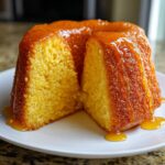A moist Bacardi Rum Cake, glazed with a rich syrup, sitting on a white plate with a slice removed to show the texture.