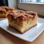 Close-up of a moist slice of coffee cake featuring a thick, crumbly cinnamon streusel topping.