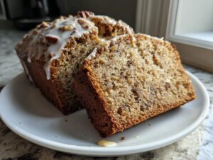 A loaf of sweet alabama pecan bread, sliced to show the moist interior, topped with a white glaze and pecans.