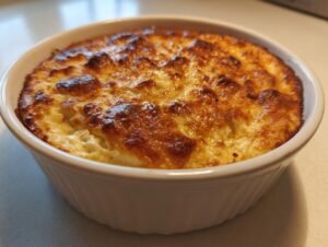 A close-up of a hot baked crab dip in a white ceramic dish with a perfectly golden brown, bubbly top.