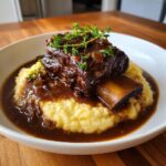 A single serving of tender braised short ribs instant pot served over creamy polenta with rich gravy and thyme.