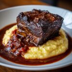 A perfectly cooked, dark braised short ribs served atop creamy yellow polenta with rich sauce.