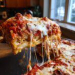A mouthwatering slice of crockpot ravioli lasagna no meat being lifted, showing extreme cheese pull.