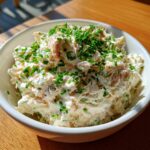 A creamy bowl of cold crab dip recipe, generously topped with freshly chopped green chives.
