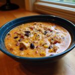 Close-up of a rich, creamy bowl of chicken taco soup loaded with chicken chunks, black beans, and corn.