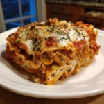 A generous, cheesy slice of crockpot ravioli lasagna topped with melted mozzarella and herbs.