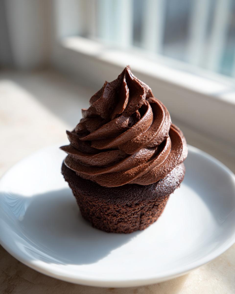 A single chocolate cupcake topped with a generous swirl of rich dark chocolate buttercream frosting.