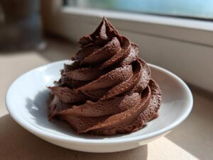 A perfect swirl of rich, dark chocolate buttercream frosting piped onto a small white dish.