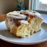 A close-up of a fluffy, iced cinnamon roll, showcasing the soft interior and rich cinnamon swirl from tiktok cinnamon rolls cooking with karli.