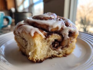 Close-up of a fluffy, iced cinnamon roll, showcasing the soft interior and sweet glaze from tiktok cinnamon rolls cooking with karli.