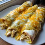 Close-up of three hatch green chile chicken enchiladas covered in melted white and orange cheese.