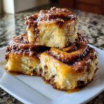 Close-up of three gooey, glazed hawaiian cinnamon rolls stacked on a white plate.