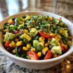 Close-up of a vibrant healthy southwest salad featuring avocado, corn, black beans, and tomatoes.