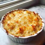 Close-up of hot, baked Maryland Crab Dip with a bubbly, browned cheese topping in a white ramekin.
