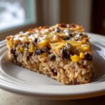 A hearty slice of black bean and rice casserole topped with melted, golden cheese, served on a plate.