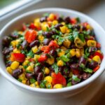 Close-up of a bright, colorful black bean salad mixed with yellow corn, red bell peppers, and fresh cilantro.
