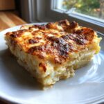 A decadent, square slice of potatoes au gratin featuring creamy layers and a deeply browned, cheesy crust.